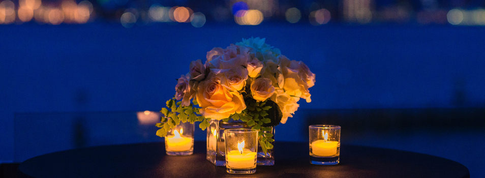 candle lit table with flowers overlooking the water at night