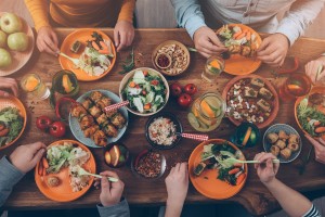 Camera angle from the top over a group of people sitting around a wooden table with food on orange plates