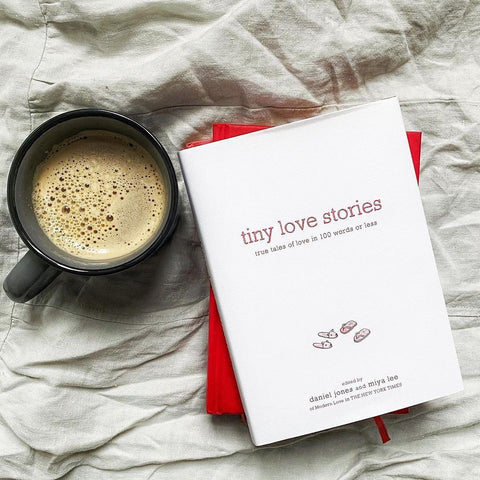 Photo of Tiny Love Stories book on a bed with a cup of coffee