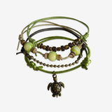 Stackable Sea Turtle Bracelet 4 piece set. Olive green cord bracelets are adjustable. Displayed with a bronze sea turtle charm and green, coconut beads. Stack bracelets are handmade. Created by O Yeah Gifts!