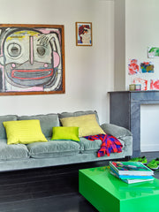 mint green velvet sofa with colored pillows and a green coffee table