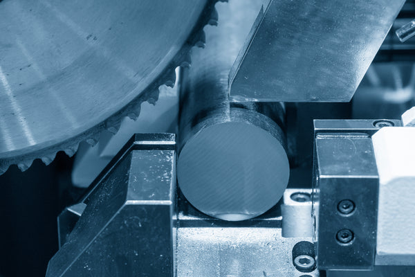 A round blade is connected to a saw. The operator is preparing to cut through a long metal rod with it.