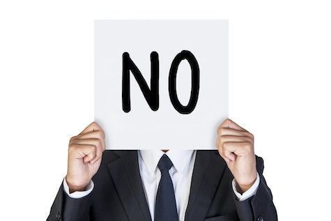 Man holding up paper that says no