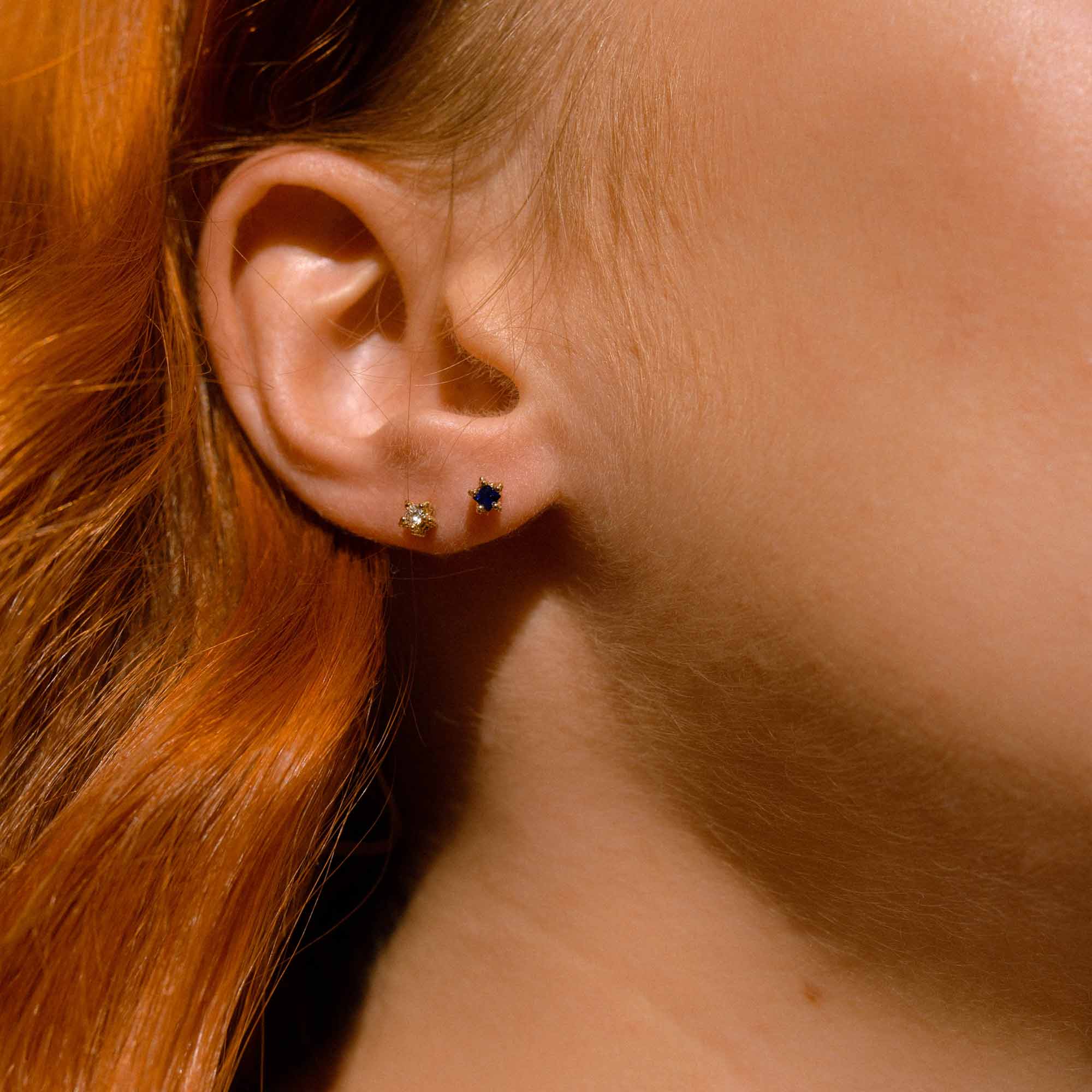 Model wears tiny blue sapphire and diamond stud earrings