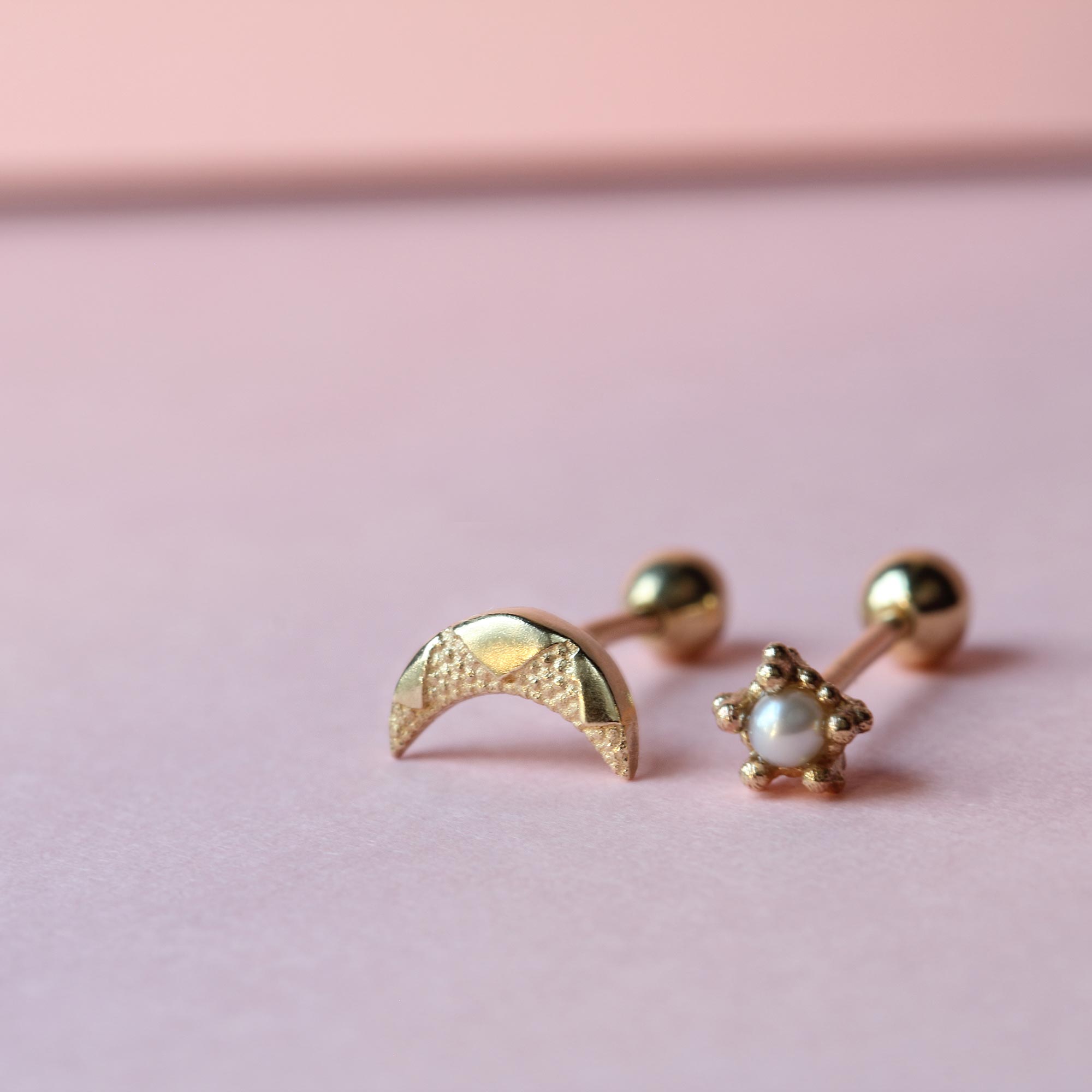 Tiny moon and tiny pearl stud earrings on pink background
