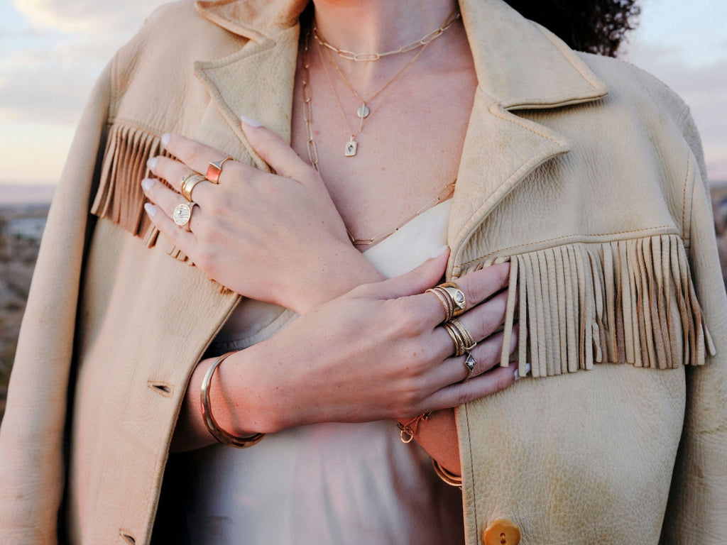 woman wearing vintage western style clothing in desert at sunset wearing stacked gold rings and chains by erin cuff jewelryerin cuff jewelry