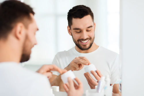 happy young man applying cream to face