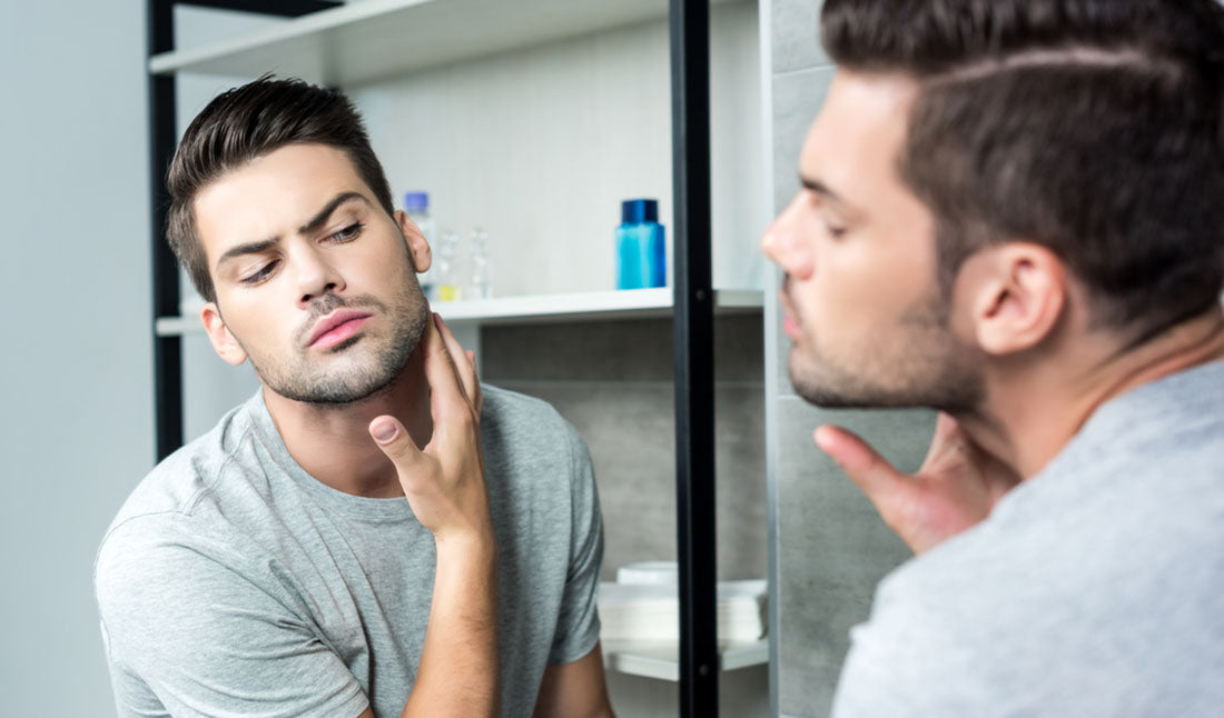 man checking beard growth in mirror