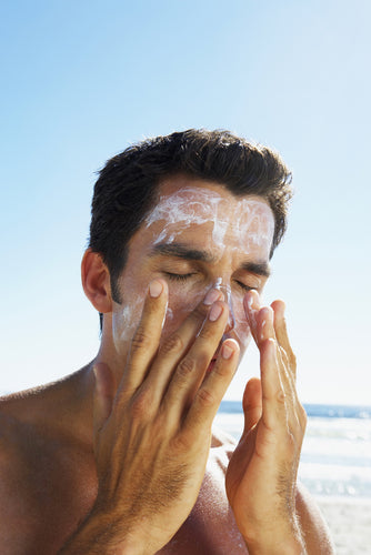 man applying sunblock on beach