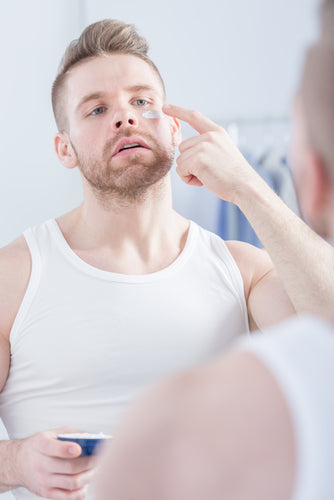 man using eye cream under eyes