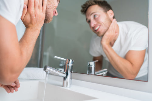 man washing face sink