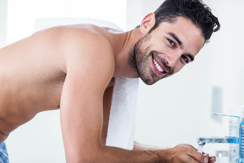 man washing his face sink