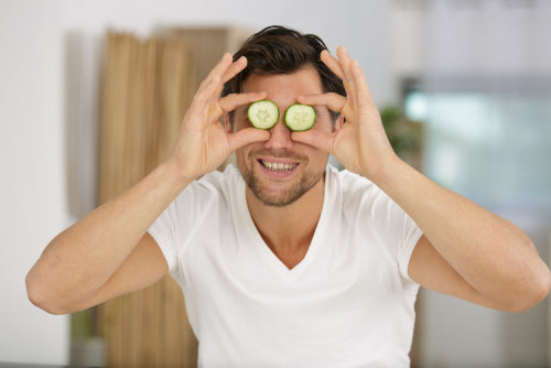 man with cucumber slices on eyes