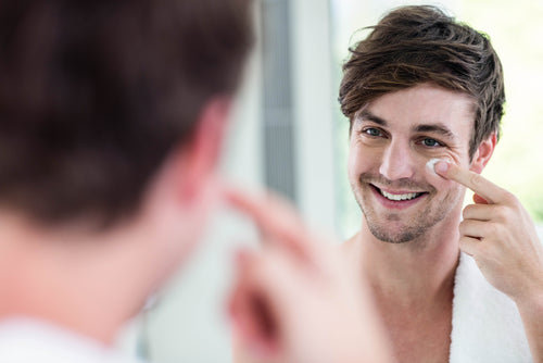 smiling man applying eye cream