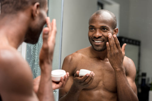 smiling man applying facial cream