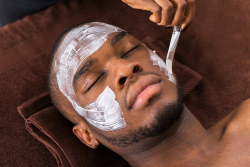 therapist applying facial mask to man
