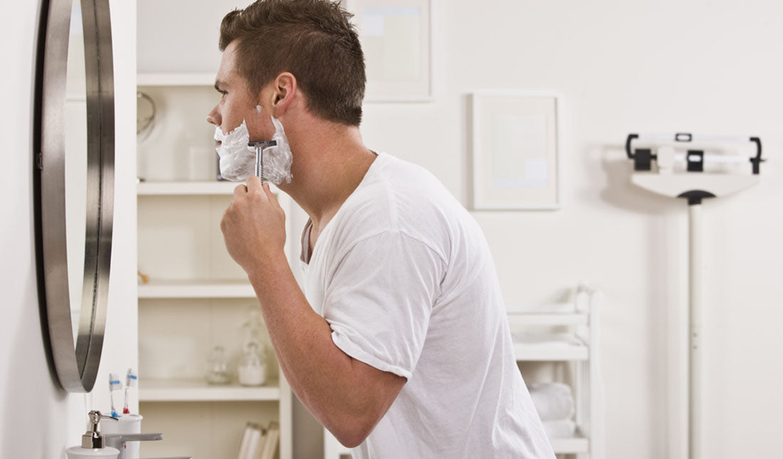 man shaving face before mirror