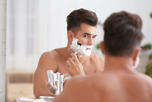young man shaving in mirror