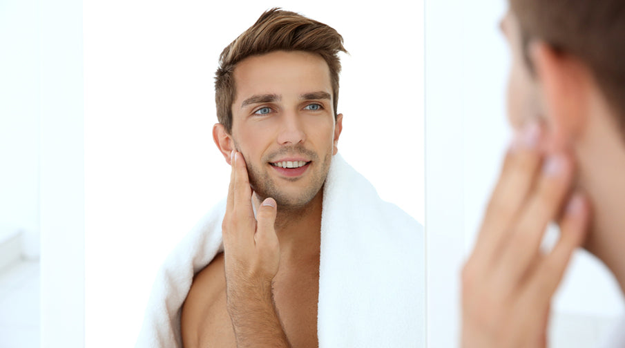 young man touching face in front of mirror