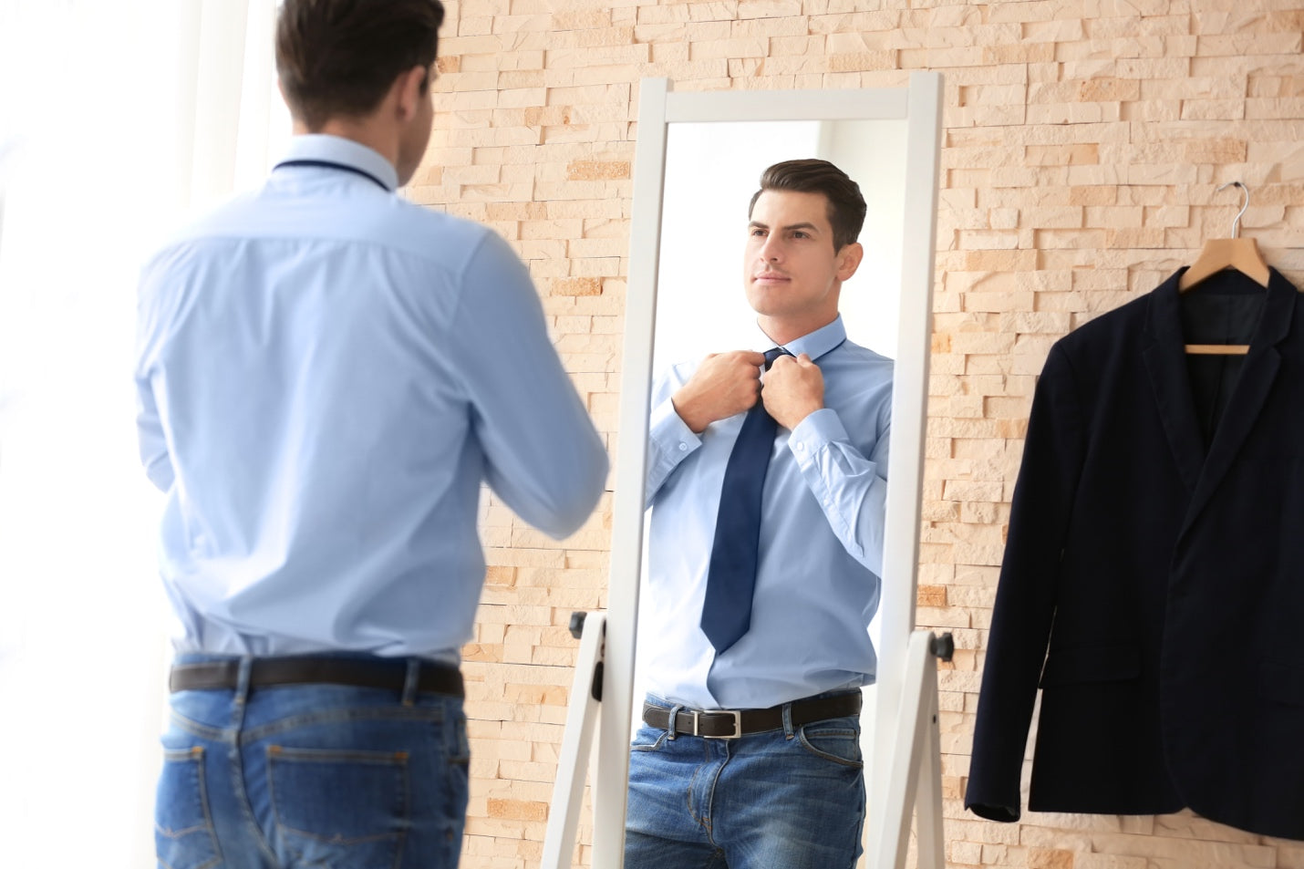 Young professional man looking at himself in a mirror 
