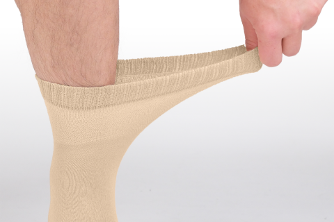 Close-up of a person wearing light beige specialty socks designed for diabetes management, highlighting the stretch and comfort of the fabric.