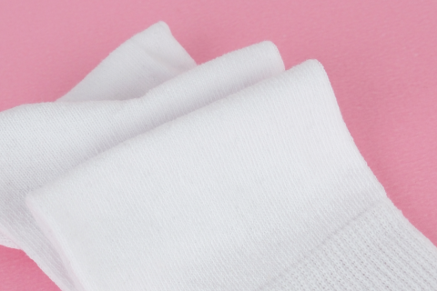 White crew socks are presented on a pink background, highlighting their simple design and comfort.