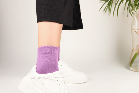 A person wearing lavender Hugh Ugoli socks with white sneakers, showcasing a stylish and comfortable casual look.