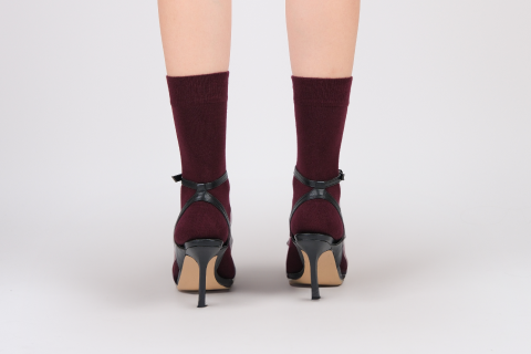 View from behind showing Hugh Ugoli's maroon socks elegantly styled with strappy black high heels, showcasing a chic and bold look.