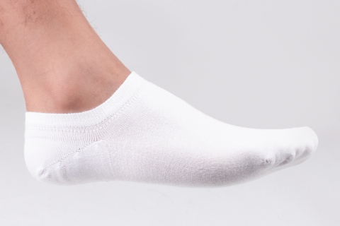 Close-up of a foot wearing a white no-show Hugh Ugoli sock, showcasing a clean and minimalist style.