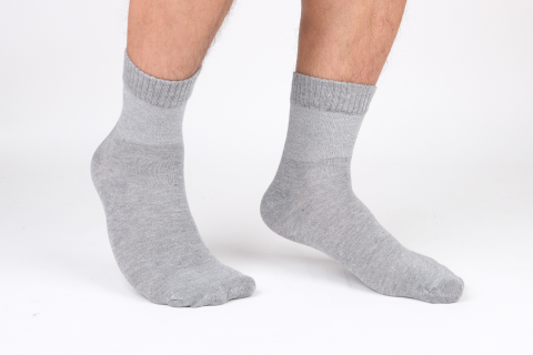 A person wearing a pair of Hugh Ugoli's gray crew socks, showcasing the snug fit and classic design suitable for everyday wear.