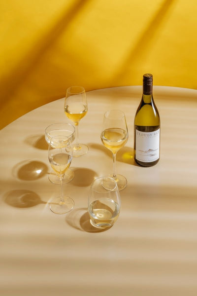 cloudy bay white wine bottle and glasses with yellow background