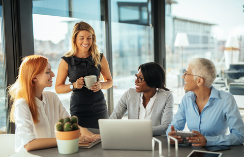 4 femmes souriantes en train de participer à une réunion