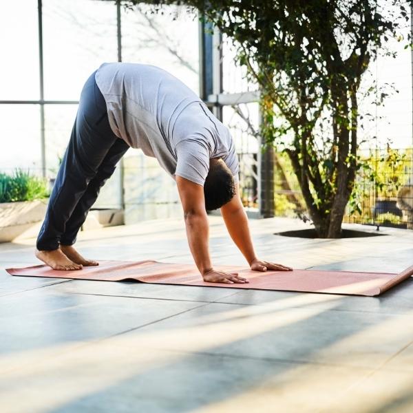 Man Performing Downward Facing Dog Exercise At Home