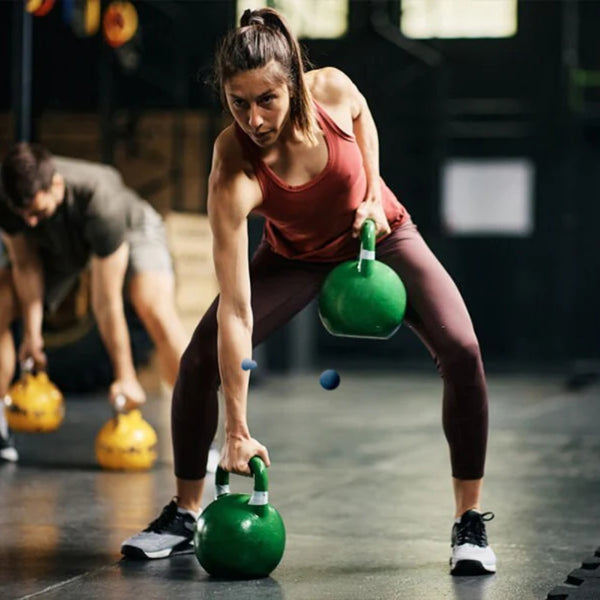 Woman using Green Kettlebells in Gym