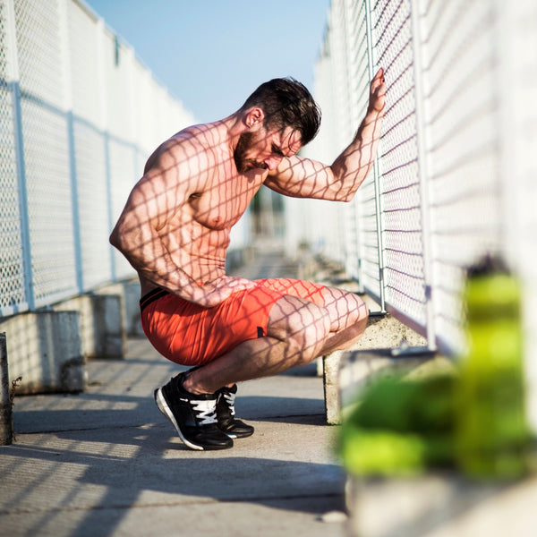 Man hunched over resting on a bridge after running