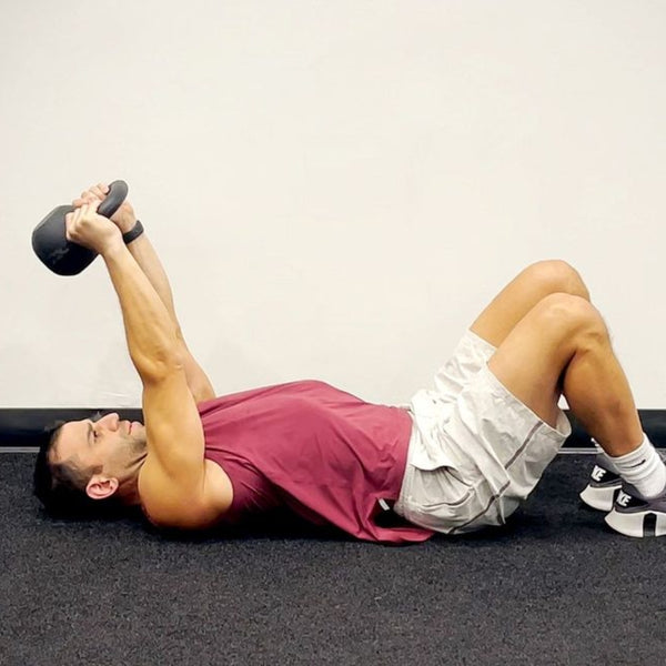 Man lying down holding a Kettlebell above head