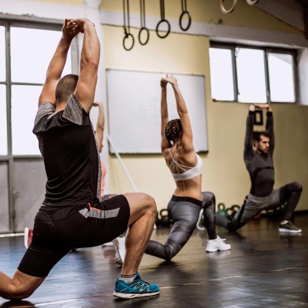 Group Performing Lunge Reach Exercise In Gym