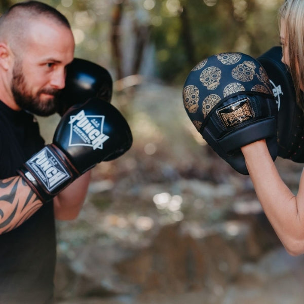 Man sparing with lady outdoors using Punch Fitness Gloves and Pads