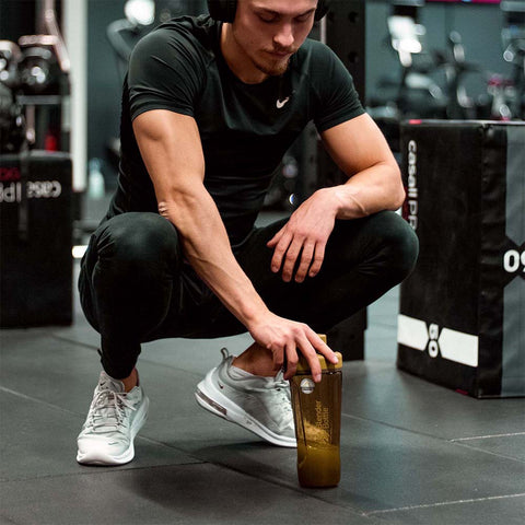 Man kneeling while taking a breather during bodybuilding workout at the gym