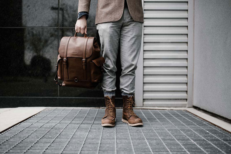 Man holding a leather backpack