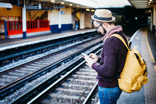 A man with a yellow backpack at a trainstation
