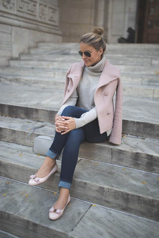 Model wearing a light pink blazer sitting on steps