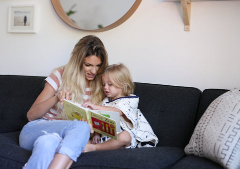 mother and child reading a book on a couch before bedtime