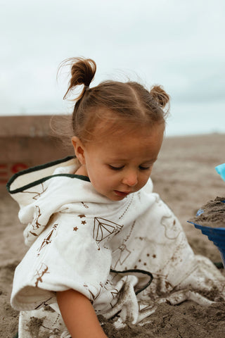 little girl playing in the sand wearing kindhood hooded poncho towel in kenai print