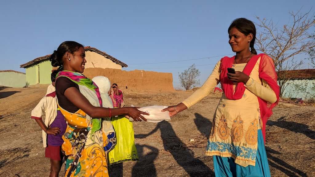 women handing pads to another woman