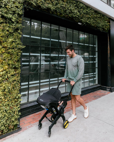 Dad pushing baby in a Doona car seat and stroller