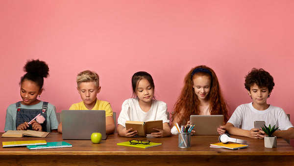 Children at table with their books and devices