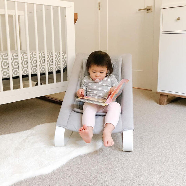 Little Girl in a Bamboo 3DKnit Bouncer is reading