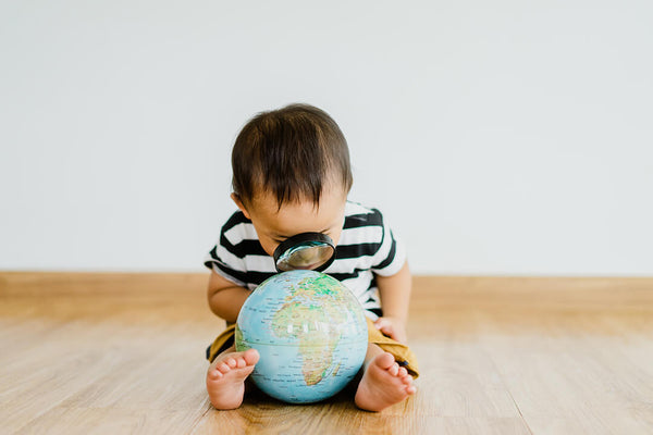 Child Looking at the Globe with Magnifying Glass