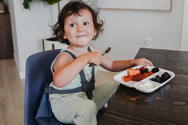 Boy eating fruits sitting on Pop-Up Booster